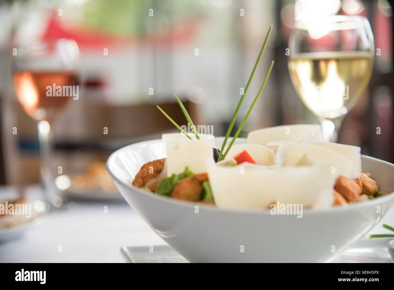 Schöne Aufnahme von Salat garniert. Zwei Gläser Wein im Hintergrund. Perfekte Restaurant für Mittag- Foto. Stockfoto