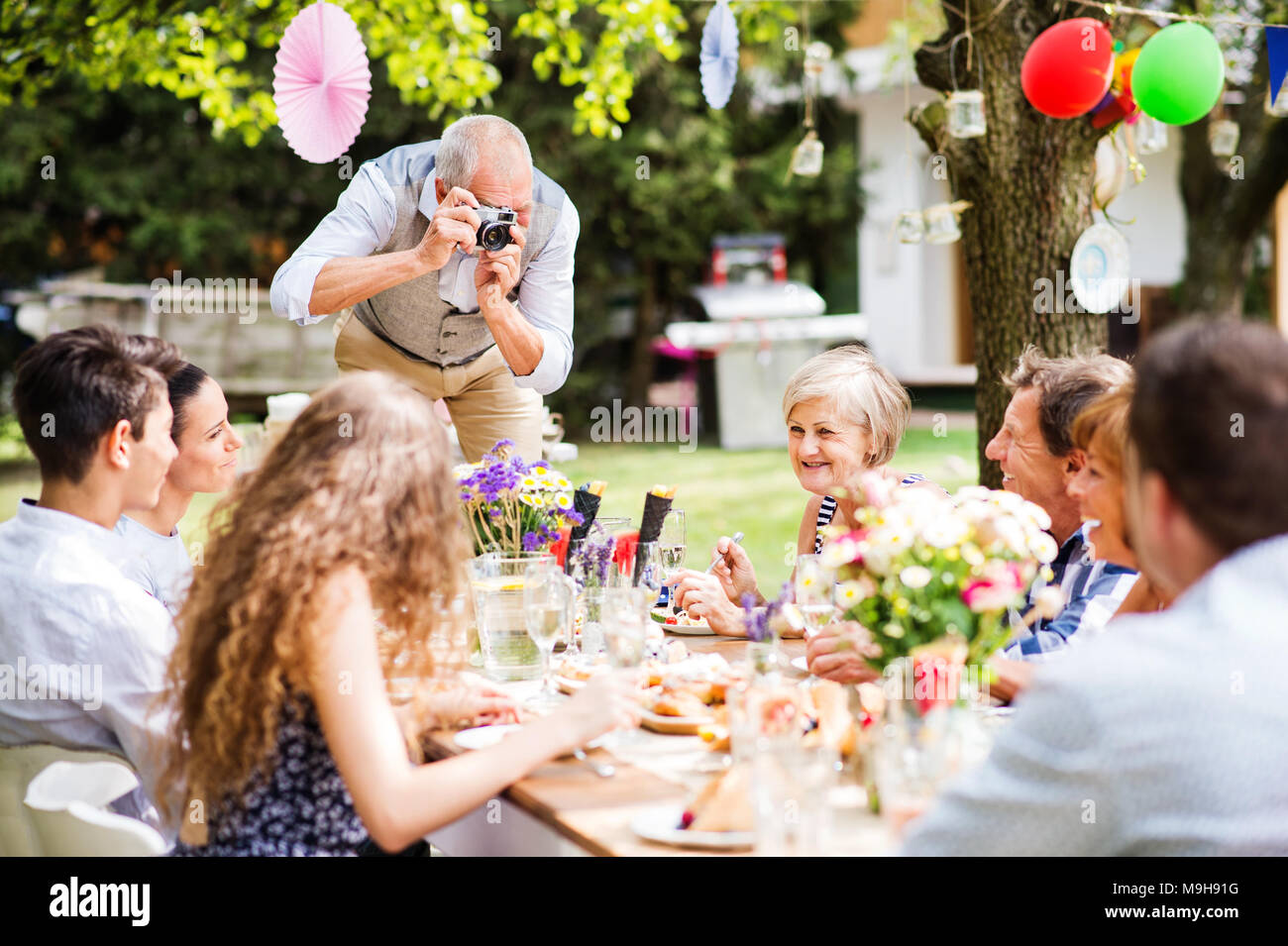 Familie Feier draußen im Hinterhof. Big Garden Party. Großvater unter Foto mit einer Kamera. Stockfoto