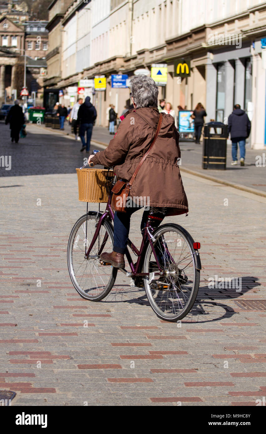 Eine ältere Frau Radfahren auf einem alten Großmutter Fahrrad entlang der Innenstadt Straße an einem sonnigen Frühlingstag in Dundee, Großbritannien Stockfoto