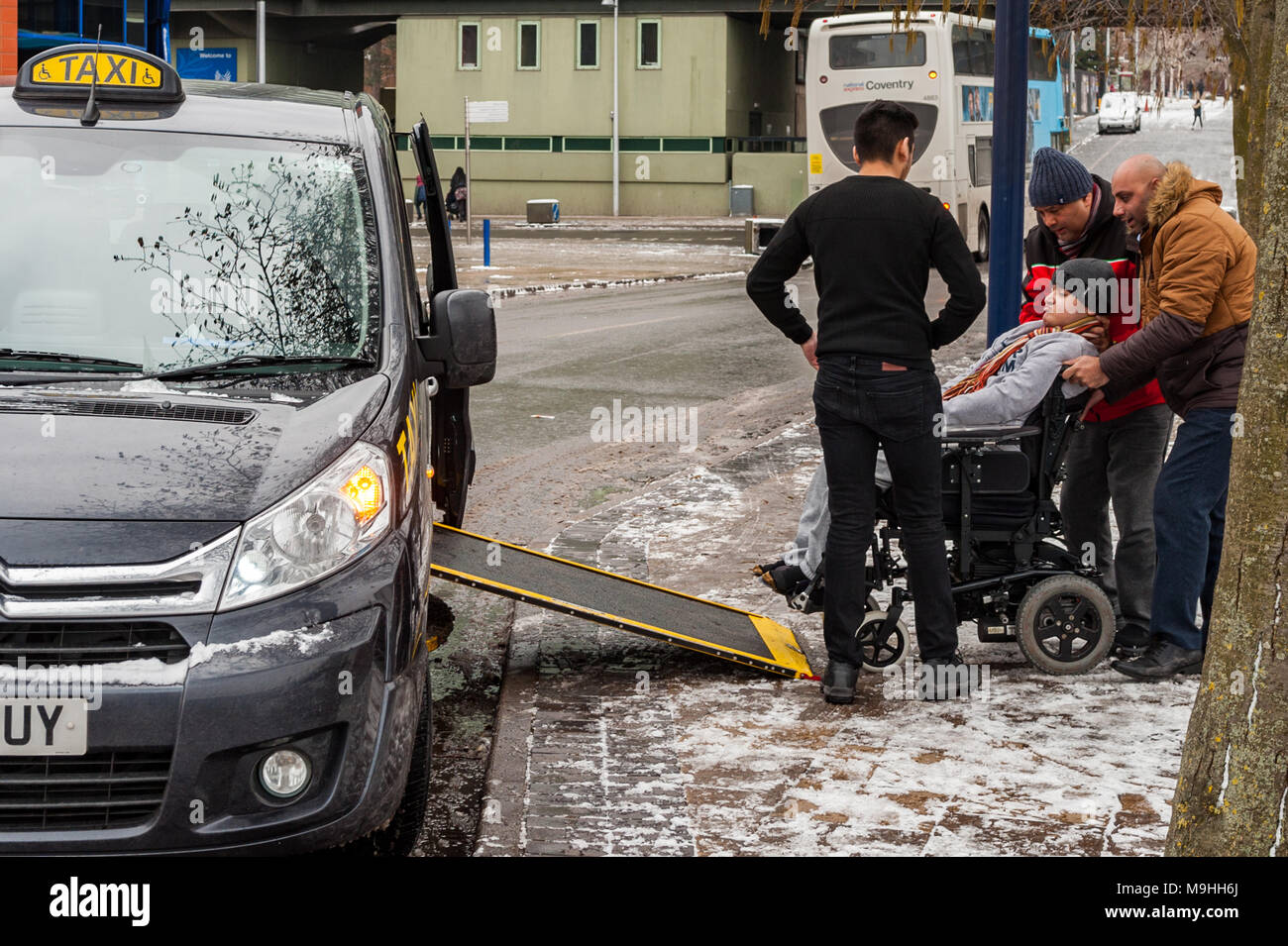 Rollstuhlfahrer geholfen wird aus einem Black Cab/Taxi am Pool Wiese Busbahnhof, Fairfax Street, Coventry, West Midlands, UK. Stockfoto