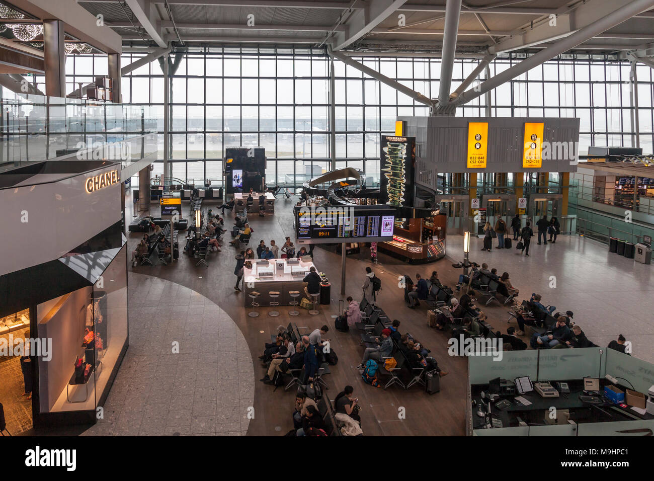 Flugreisende wartet im Abflugbereich des Flughafens Heathrow, Terminal 5. Sitzecke, Telefon Ladestationen, Caviar House, Chanel, Menschen, Stockfoto