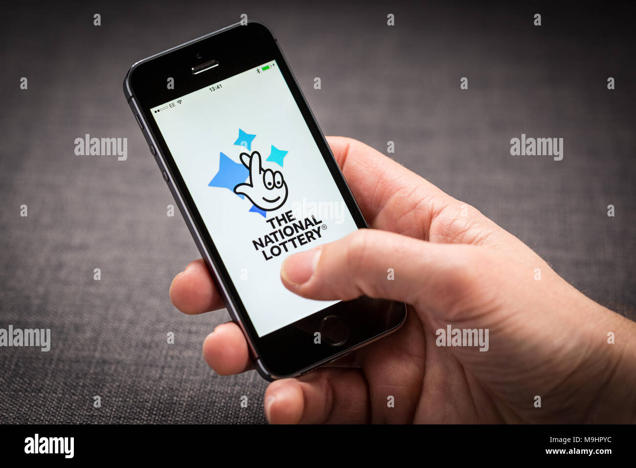 Ein Mann mit der Nationalen Lotterie App auf dem iPhone Stockfoto