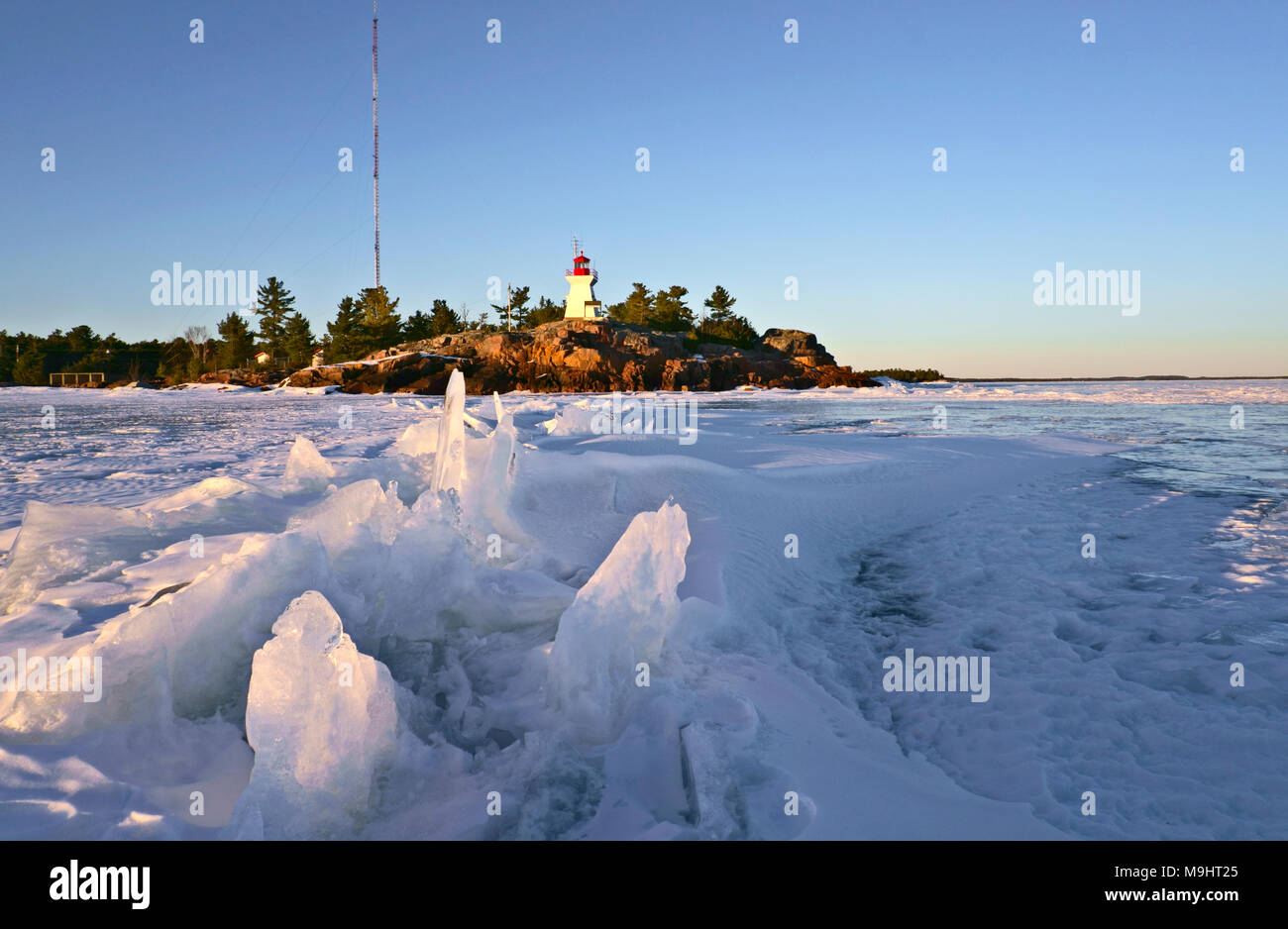 Georgian Bay Killarney Leuchtturm, im Jahre 1850 erbaut, mit gefrorenen See und dramatische Eisformationen in der Abenddämmerung im Frühjahr Stockfoto