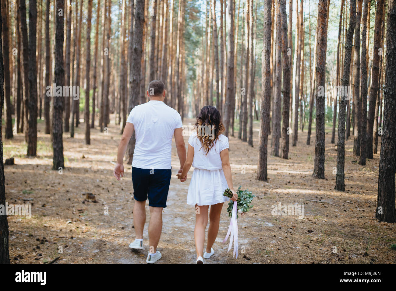 Paar Liebhaber halten sich an den Händen und laufen weg in den Wald. Frau und Mann in Liebe Walking im Freien. Hochzeit. Mann und Frau. Stockfoto