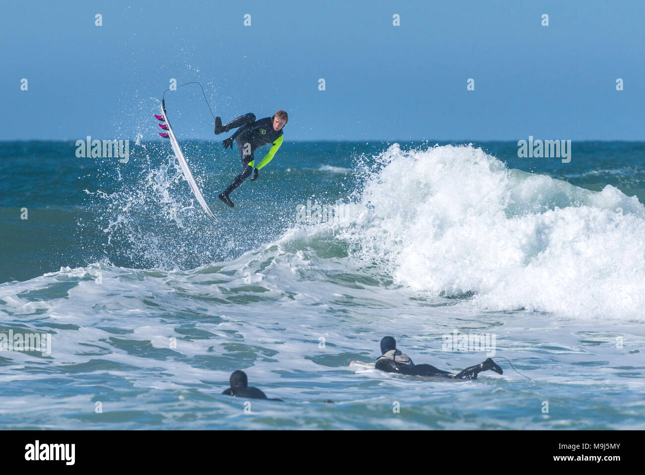 Ein Surfer einen spektakulären Sprung von der Spitze einer Welle an Fistral in Newquay Cornwall. Stockfoto