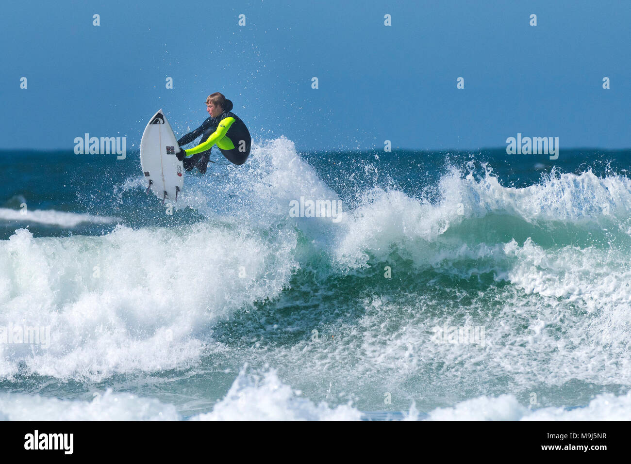 Ein Surfer eine spektakuläre Luftaufnahmen Trick von der Spitze einer Welle an Fistral in Newquay Cornwall. Stockfoto
