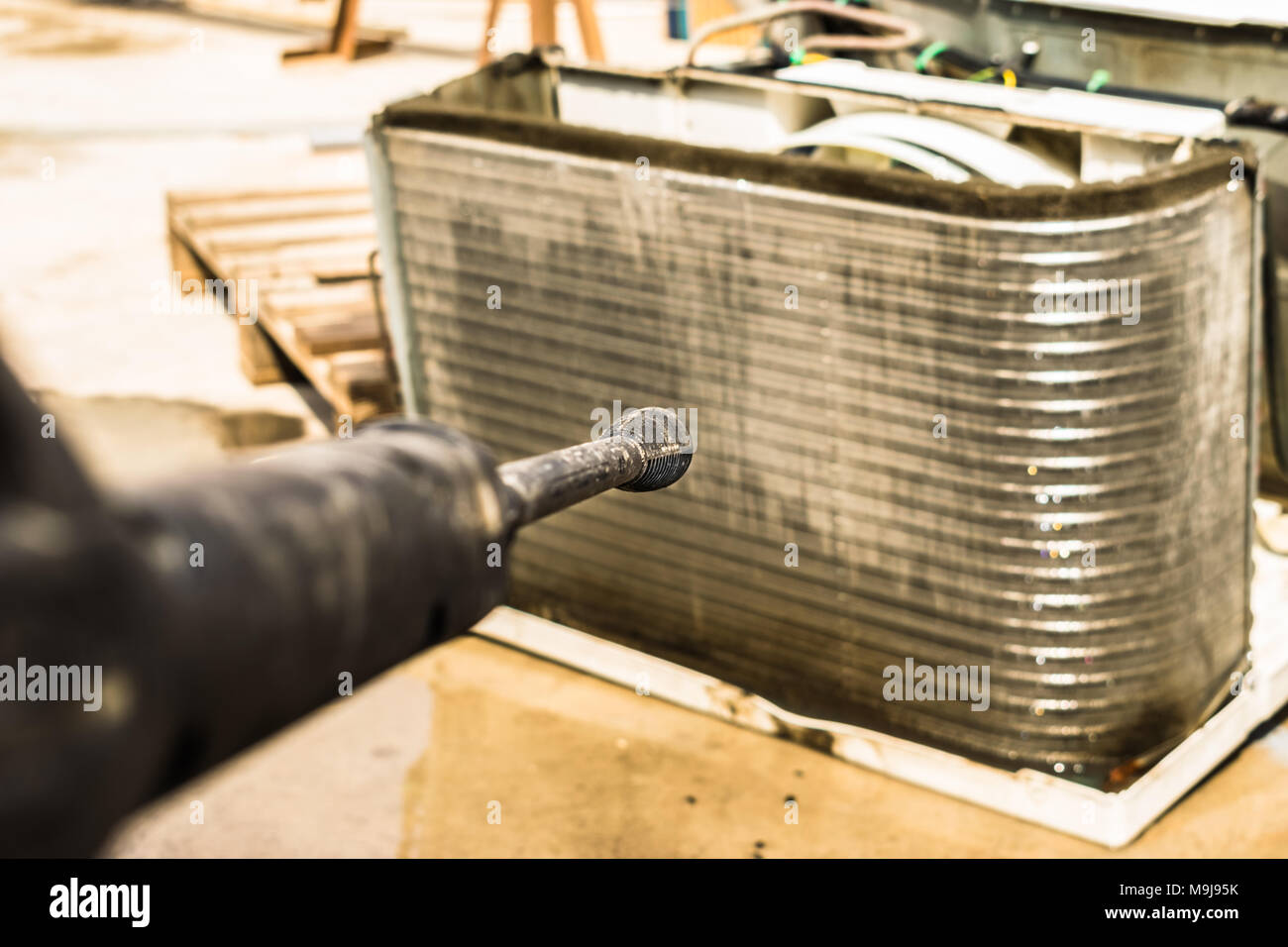 Einen professionellen Elektriker ist die Reinigung der Fenster Klimaanlage auf dem Dach eines Hauses mit seinem hohen Druck Wasser Pistole Stockfoto