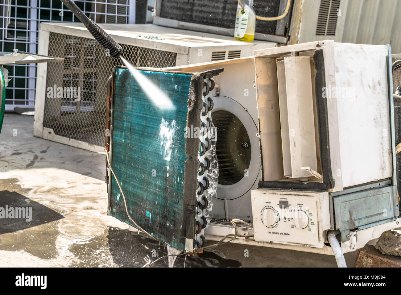 Einen professionellen Elektriker ist die Reinigung der Fenster Klimaanlage auf dem Dach eines Hauses mit seinem hohen Druck Wasser Pistole Stockfoto