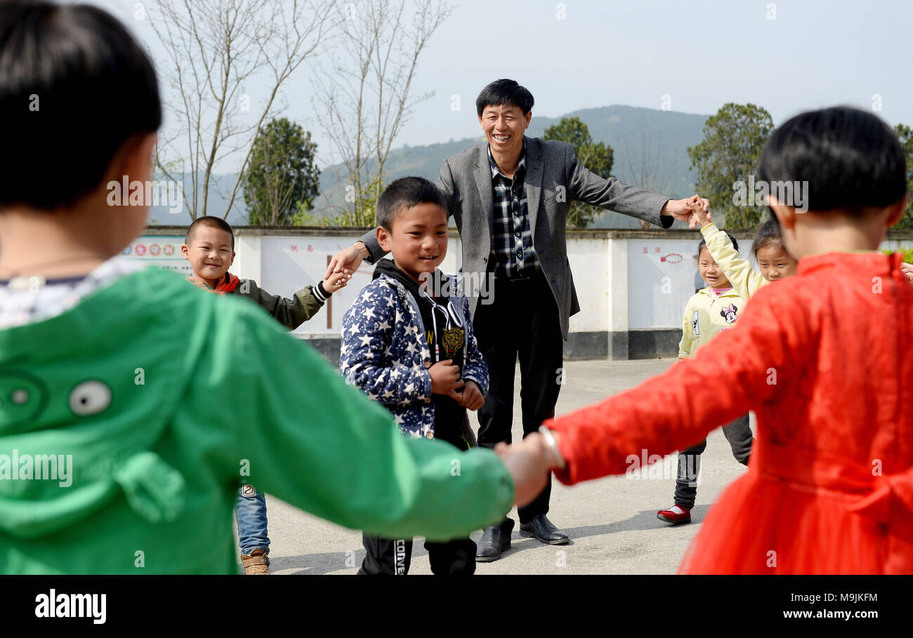 (180327) -- PINGLI, 27. März 2018 (Xinhua) - Lehrer ihr Shiping macht Übungen mit Studenten an der Schule in Xihe Stadt Pingli County im Nordwesten der chinesischen Provinz Shaanxi, 26. März 2018. Ihr Shiping, 53 Jahre alt, entschieden, hinter am Renjiaya Grundschule als Lehrer mit seiner Frau als die Zahl der Studenten, die hier wohnen, auf nur 15 gesunken. Die Schule, die in abgelegenen bergigen Gegend, 30 Kilometer von der Grafschaft. Mit der Verringerung der Bevölkerung, Ihr und seine Frau die Einzigen zwei Lehrer in der Schule. Die Pflege ihrer Studierenden, die Paare zu bestimmen Stockfoto