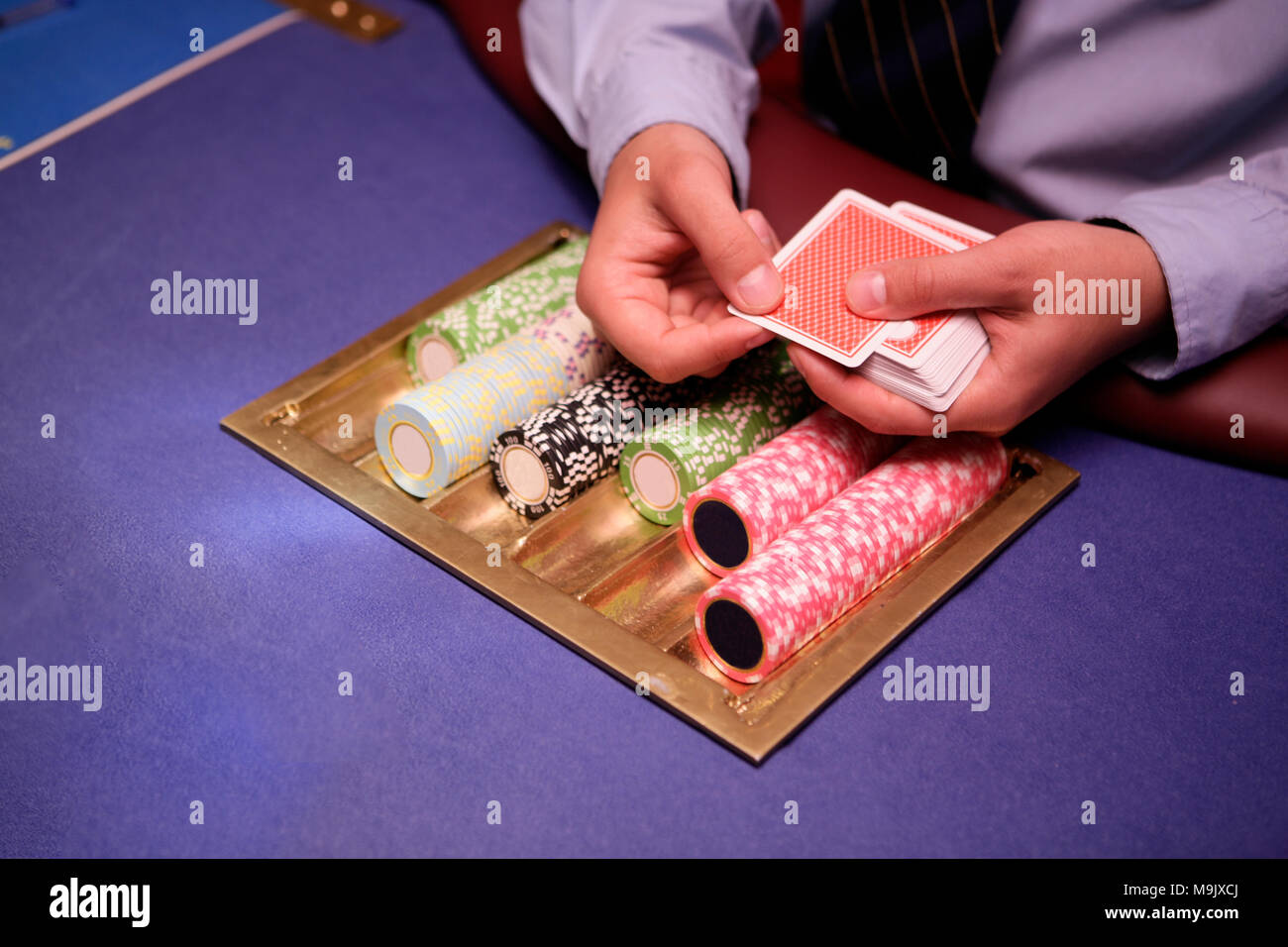 Nahaufnahme von holdem Dealer mit Spielkarten und Chips auf blauen Tabelle Stockfoto