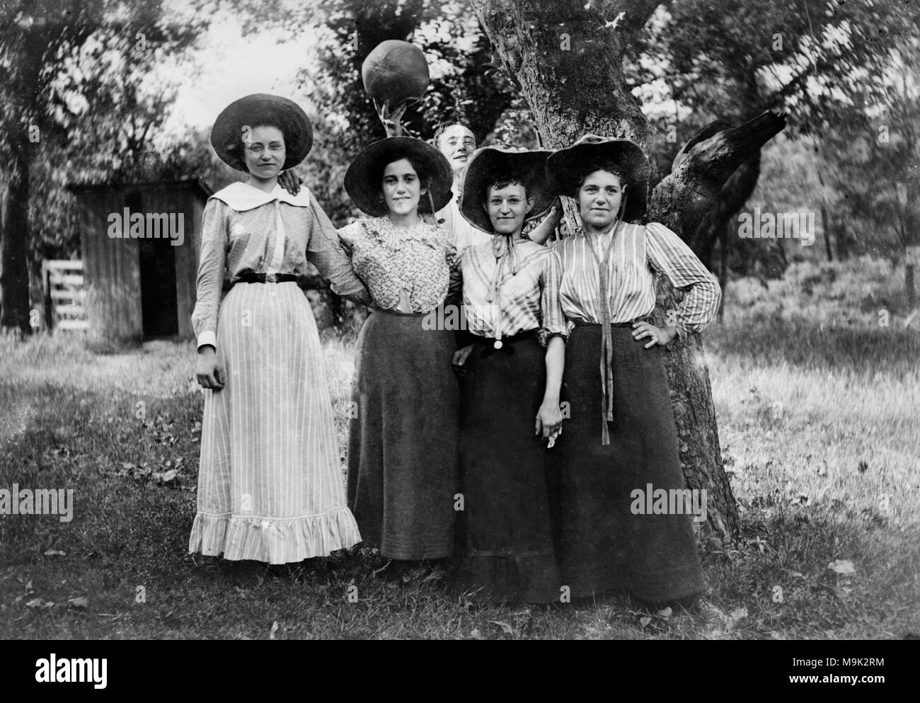 Ein junger Mann mit einem Basketball photobombs vier Frauen, die für ein Bild posiert, Ca. 1910. Stockfoto