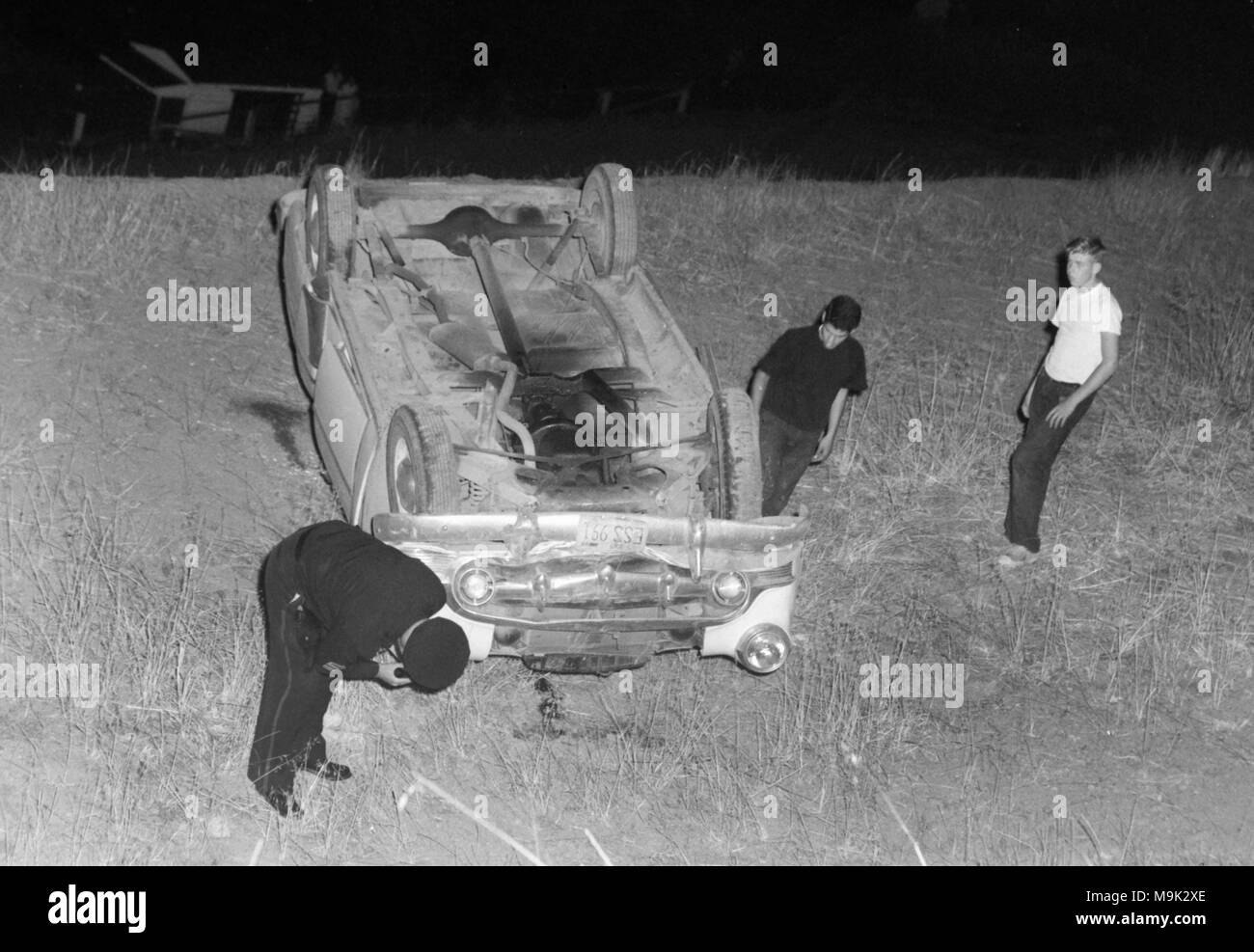 Ein Polizist untersucht, ein Auto, eine Boeschung in Kalifornien gerollt hat, Ca. 1960. Stockfoto
