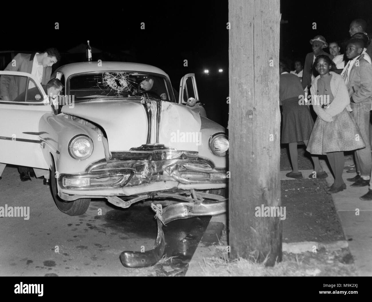 Mit Schaulustigen beobachten, ein Fahrer von einem abgestürzten Auto in Oakland, Kalifornien extrahieren, Ca. 1961. Eine Bierflasche sitzt auf dem Dach des Autos thront. Stockfoto