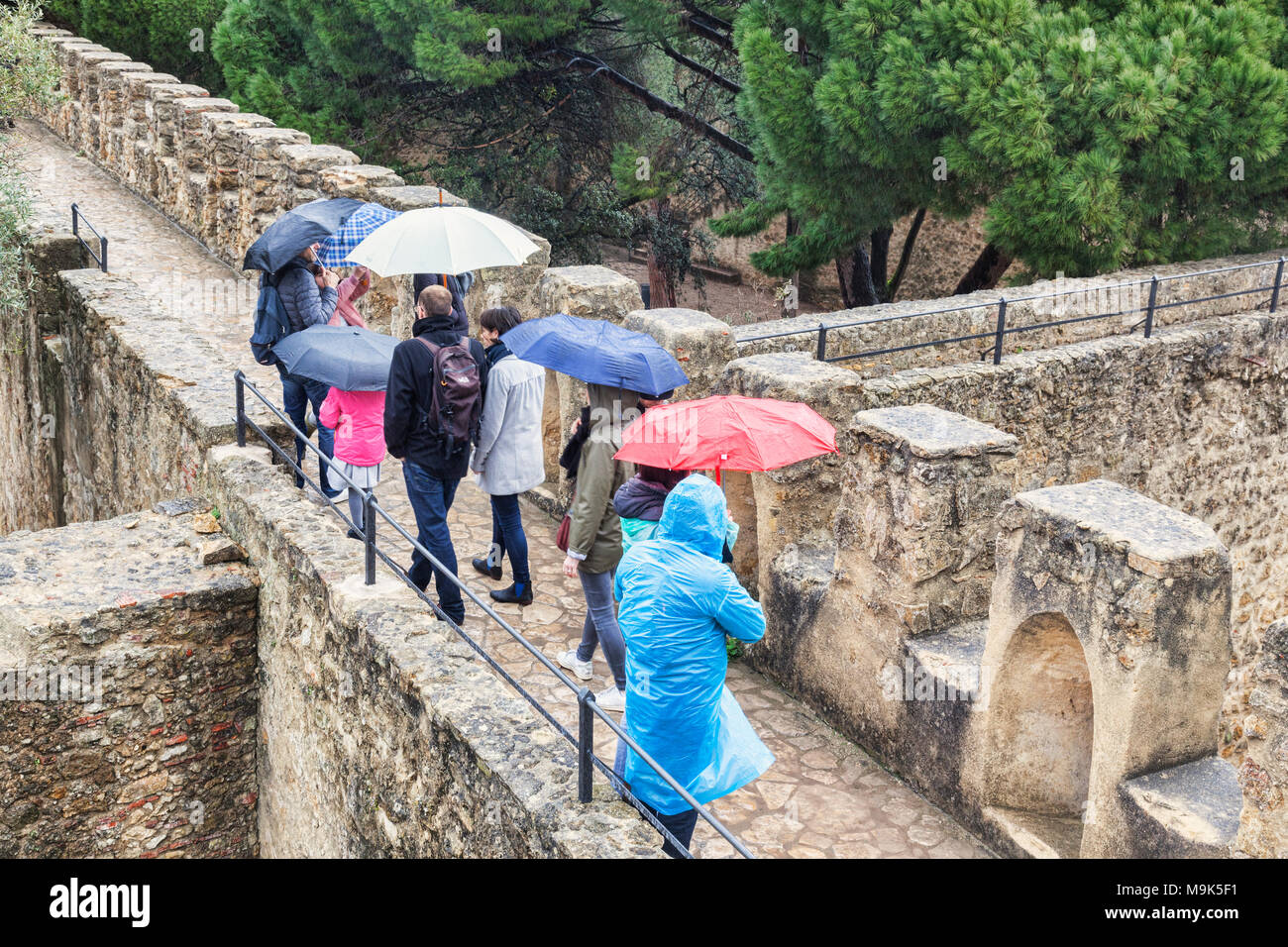 1. März 2018: Lissabon, Portugal - Touristen mit Sonnenschirmen auf den Wällen von Lissabon Kaste, Sightseeing im Regen. Stockfoto