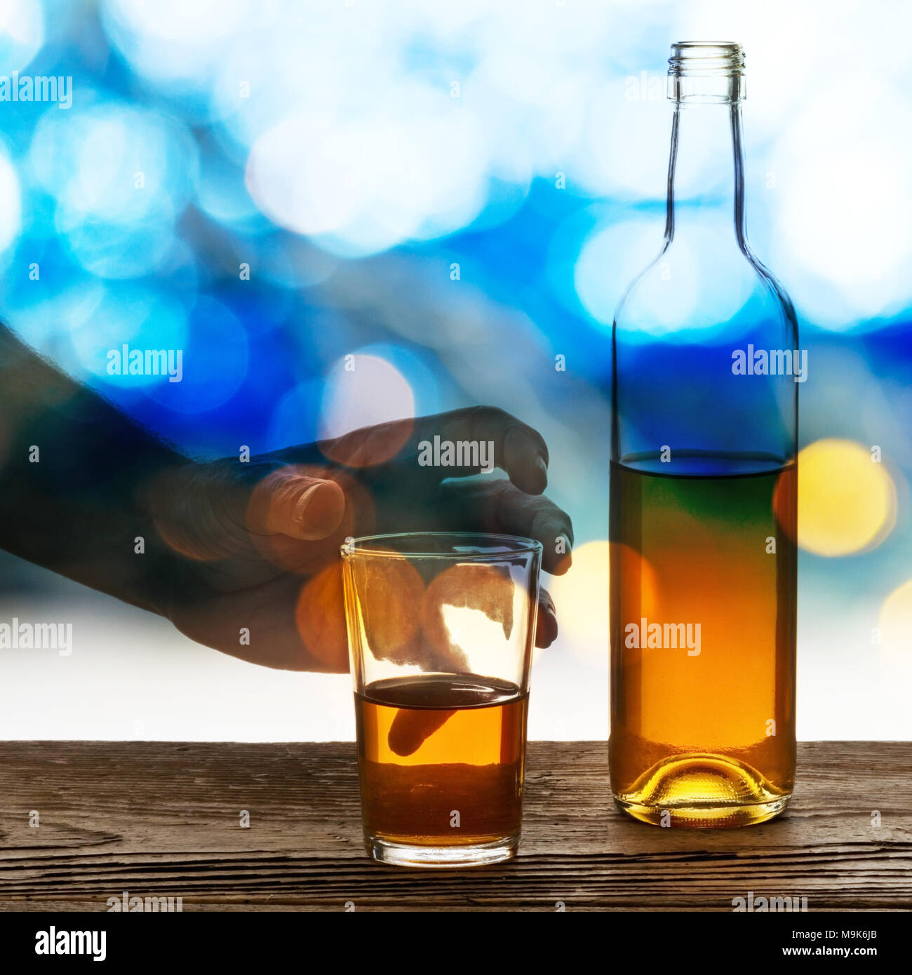 Hand mit Glas und Flasche Brandy Stockfoto