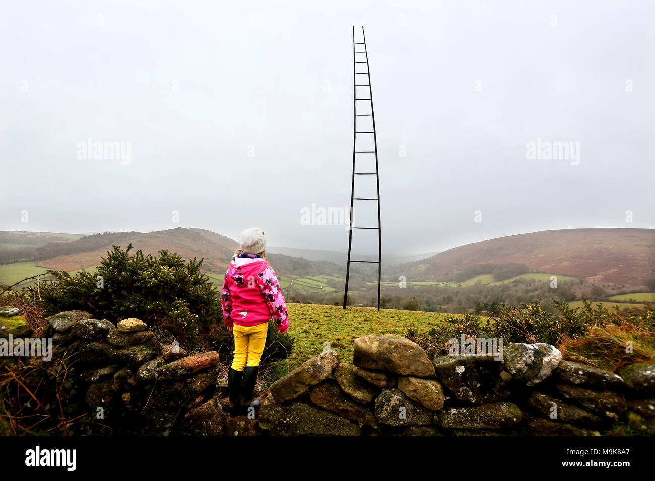 Ein junges Mädchen sieht, der zu einem gigantischen Leiter auf Dartmoor Nationalpark in Devon errichtet. Das Stück von Kunst im öffentlichen Raum ca. 100 ft Höhe. Stockfoto