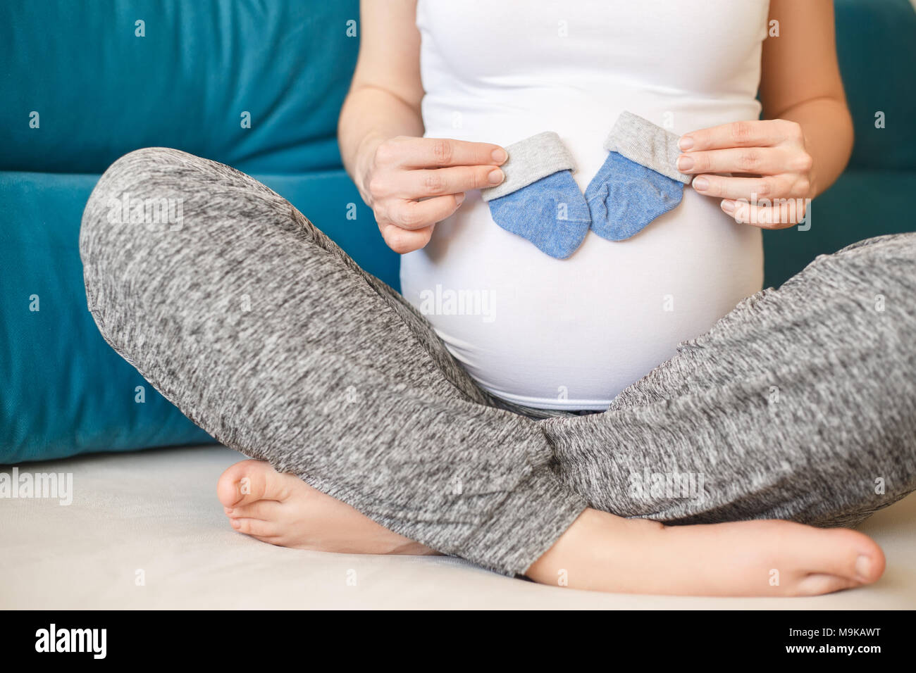 Closeup schwangere Frau mit blauen Socken auf ihren Bauch. Die werdende Mutter. Schwangerschaft, Menschen, Erwartung von baby boy Konzept Stockfoto