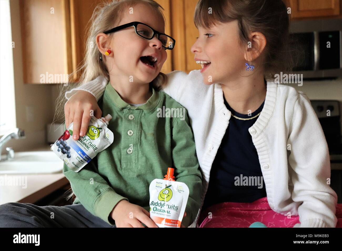 Schwestern genießen Buddy Obst in der Küche Stockfoto