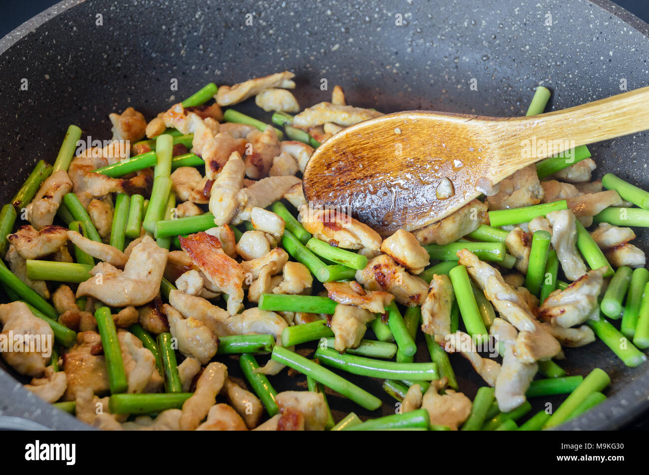 Pfeile von Knoblauch und Fleischstücke werden in einer Pfanne gebraten nach dem Rezept für das Kochen Asiatische hausgemachte Nudeln Stockfoto