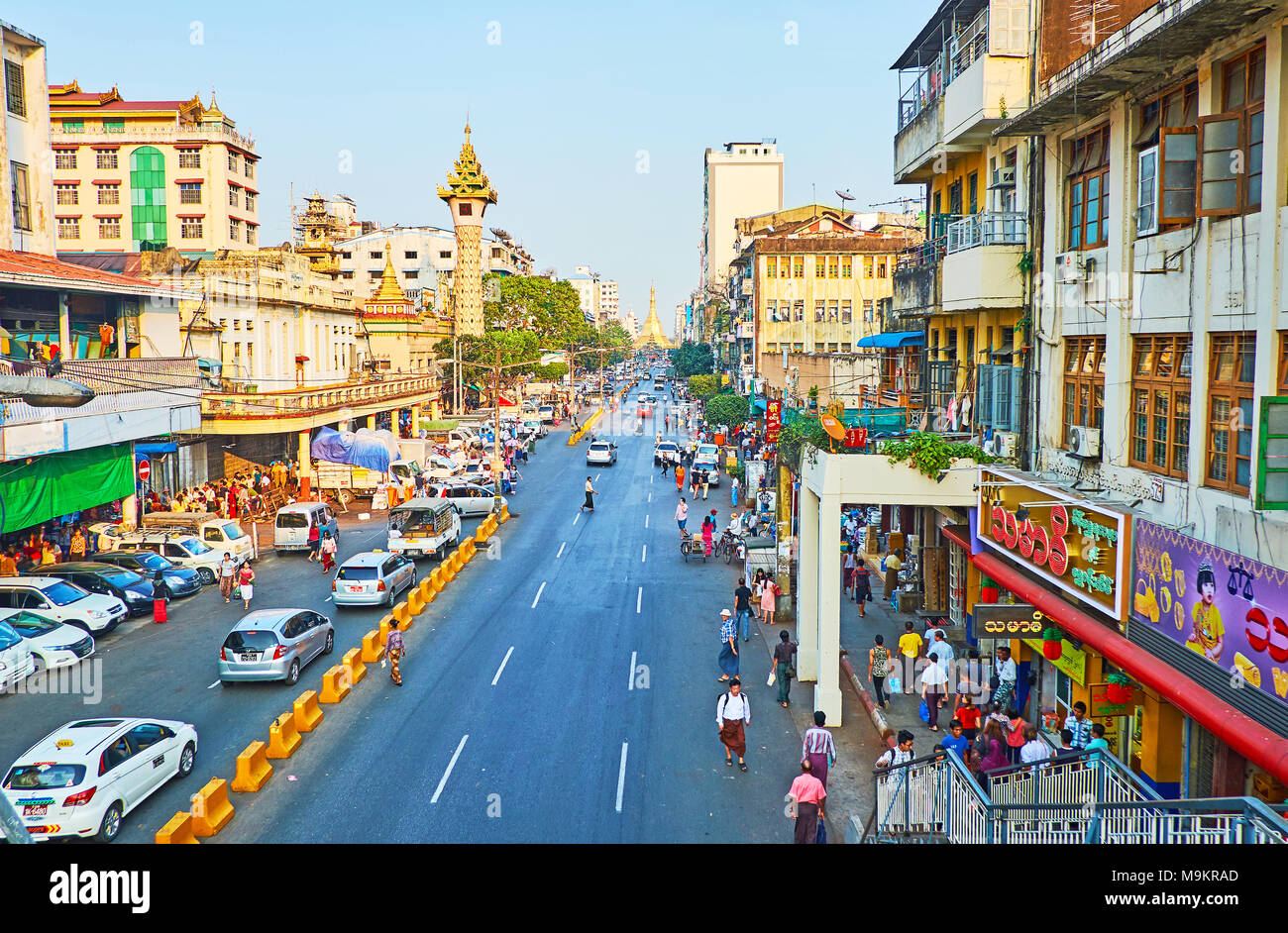 YANGON, MYANMAR - 14. FEBRUAR 2018: Die tägliche Aktivität in Maha Bandula Straße, mit einem Blick auf den Turm von Maha Theindawgui Tempel und goldene Sule Pagode o Stockfoto