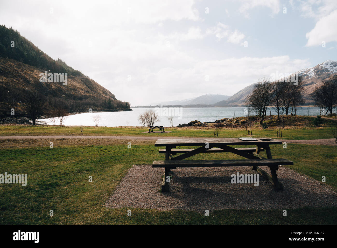 Leere Picknicktisch durch Loch Eil, Fort William, Schottland, auf einer klaren Frühlingstag. Stockfoto