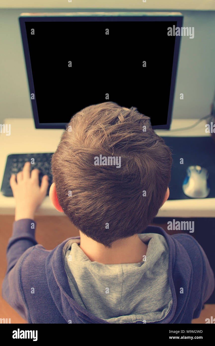 Junior Schüler mit PC, Internet Browser für Hausaufgaben und Spielen online Spiele mmorpg. Das Foto hat eine Copyspace. Stockfoto
