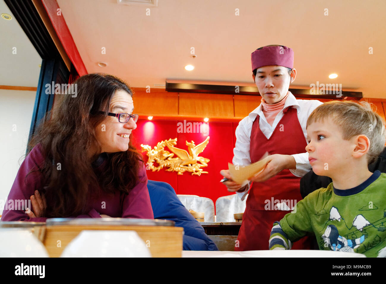 Eine Mutter an ihr fünf Jahre alter Sohn übertragen, wie Dim Sum Spezialitäten werden in einem chinesischen Restaurant serviert Stockfoto