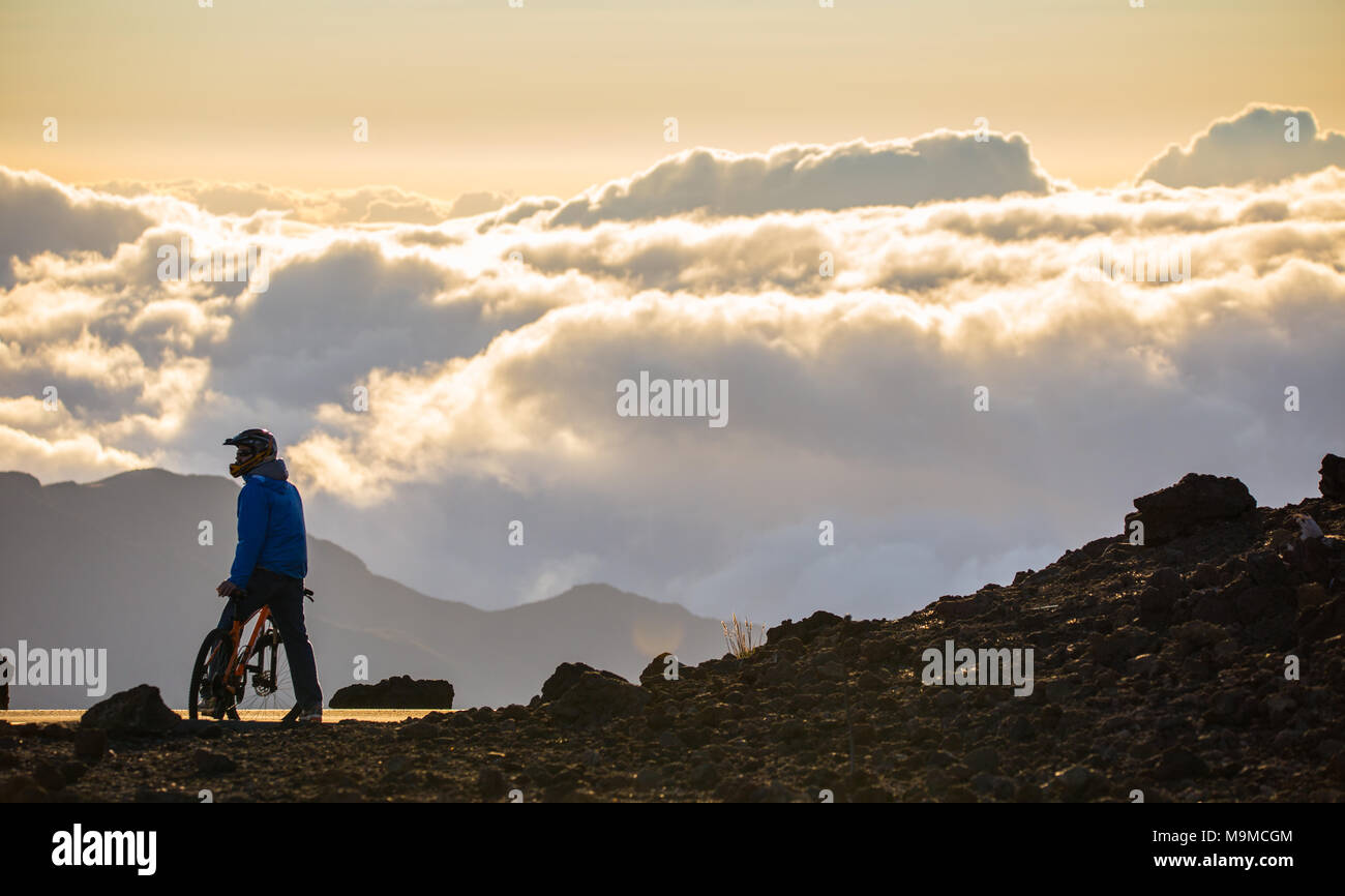 Mountainbiker auf einem Gipfel über den Wolken im frühen Morgen Sonnenaufgang am Haleakala Mounti Hawaii Stockfoto