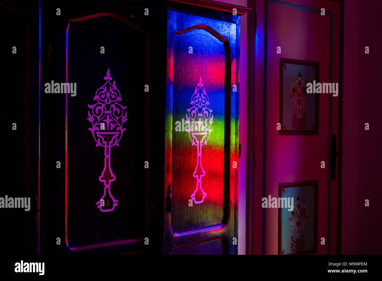 Blumenschmuck auf alten marokkanischen Holz- Spind mit roten, grünen und blauen Licht beleuchtet Stockfoto