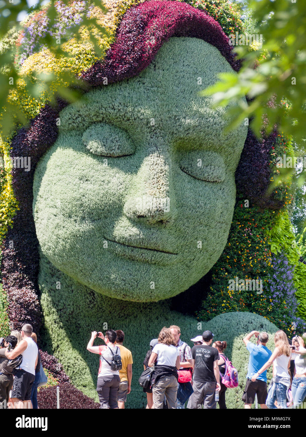 Mutter Erde und Touristen: ein riesiges pflanzlicher Skulptur des Gesichts der Mutter Erde mit einer Schar von Touristen fotografieren in der Frontseite bei MosaiCanada 150. Stockfoto