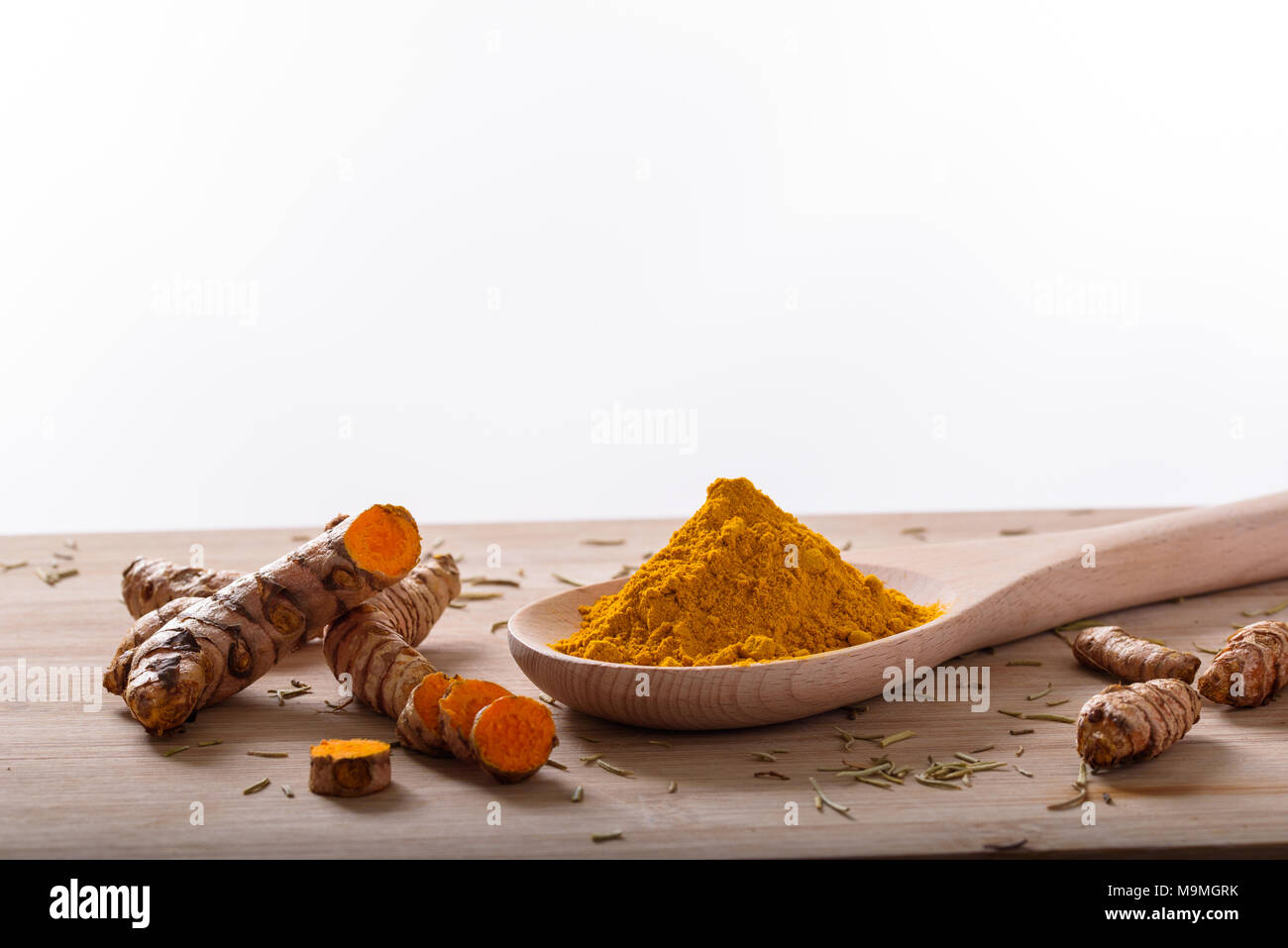 Kurkuma Pulver und Kurkuma Wurzeln auf eine Holzoberfläche mit weißem Hintergrund Stockfoto