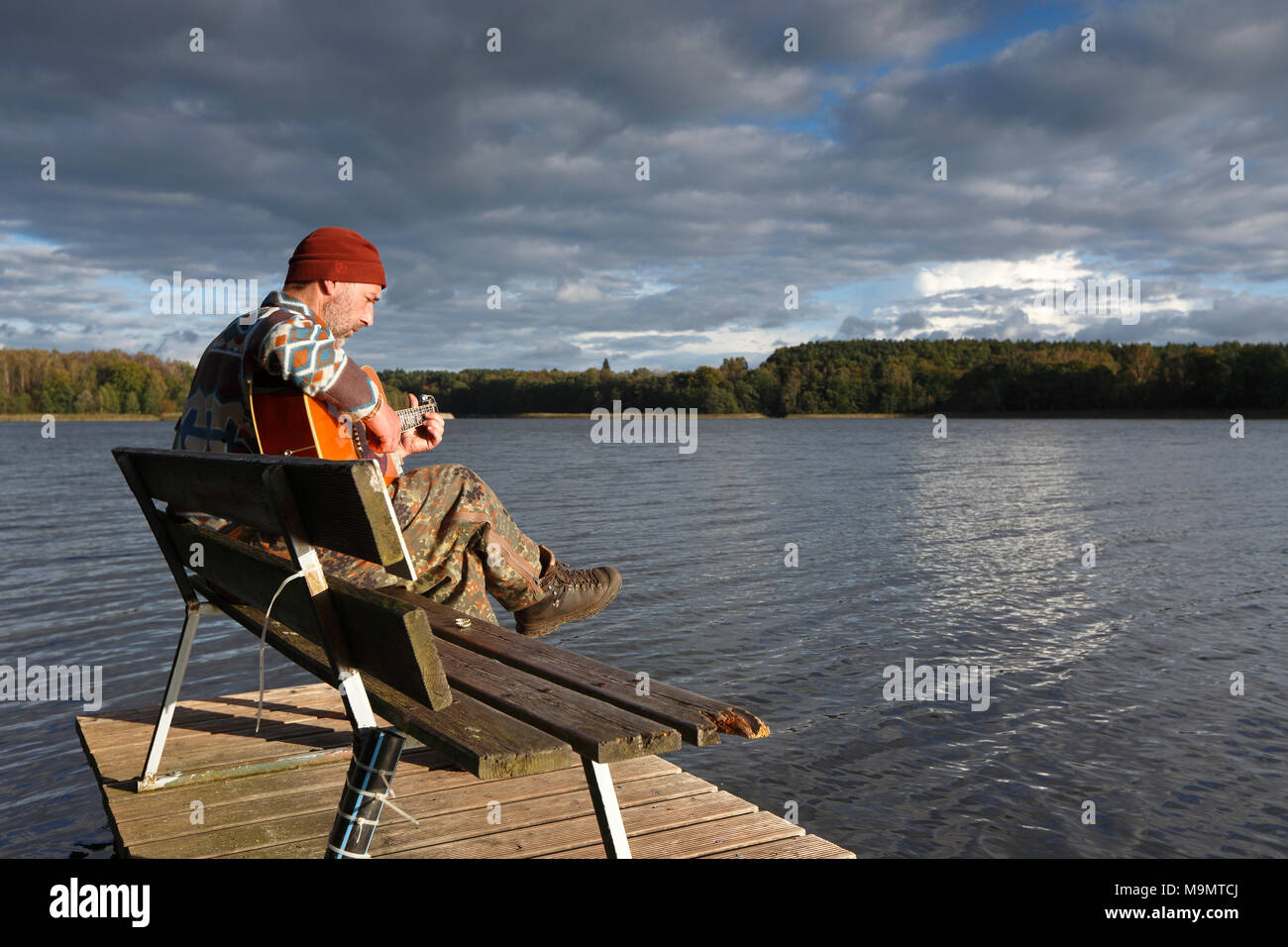 Der Mensch spielt Gitarre auf einem Boot Bootssteg am See, Mecklenburgische Seenplatte, Mecklenburg-Vorpommern, Deutschland Stockfoto