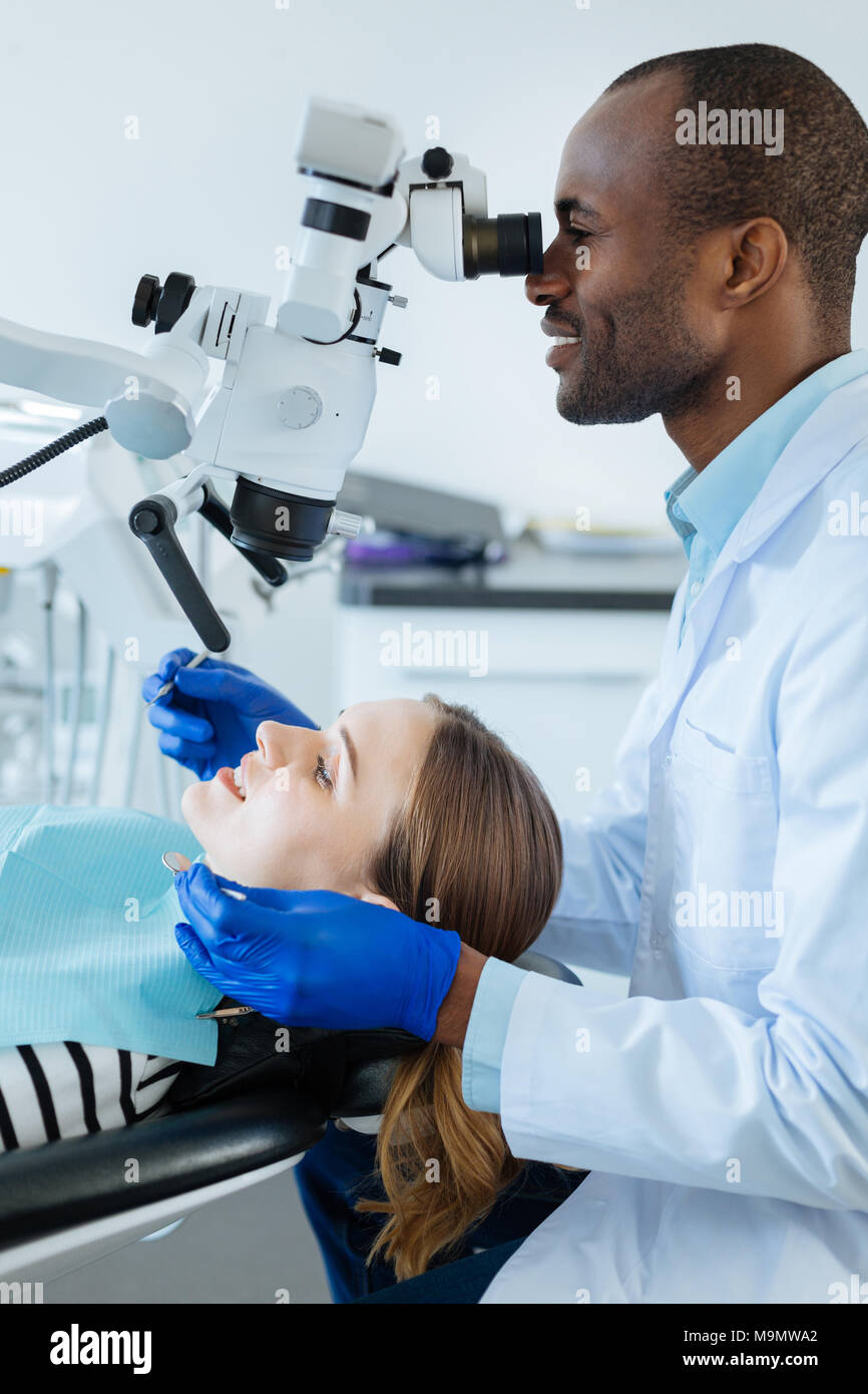 Erstklassiger Service. Die Seitenansicht eines bezaubernden weiblichen Patienten im Zahnarztstuhl liegen und in ihre Zähne durch einen männlichen Zahnarzt geprüft werden, während er Usi Stockfoto