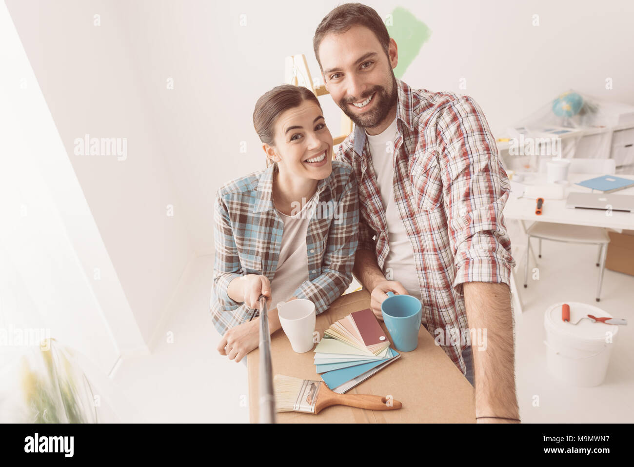 Lächelnd junges Paar Einzug in ihr neues Haus und eine Haus Makeover zu tun, nehmen sie ein Selbstporträt Stockfoto