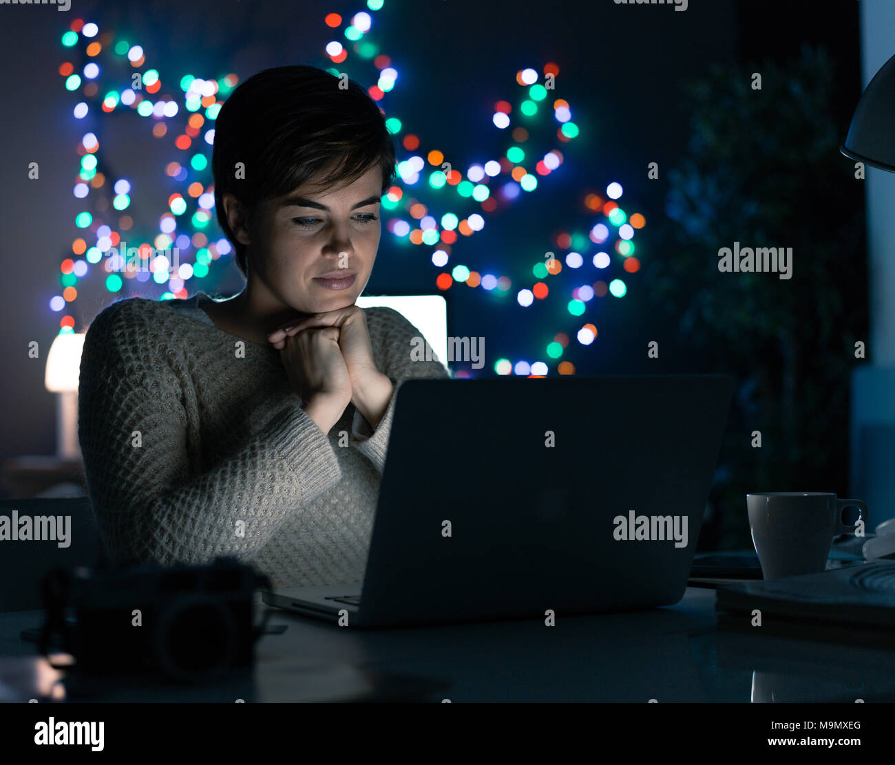 Junge Frau zu Hause spät abends zu entspannen und Filme online mit Ihrem Laptop Stockfoto