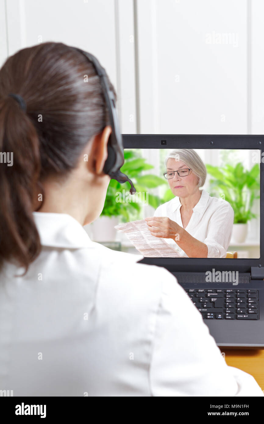 Apotheker mit Headset vor Ihrem Laptop während einer Videokonferenz mit einem älteren Patienten halten Sie die Informationen über ihre Medikamente verordnet, Stockfoto
