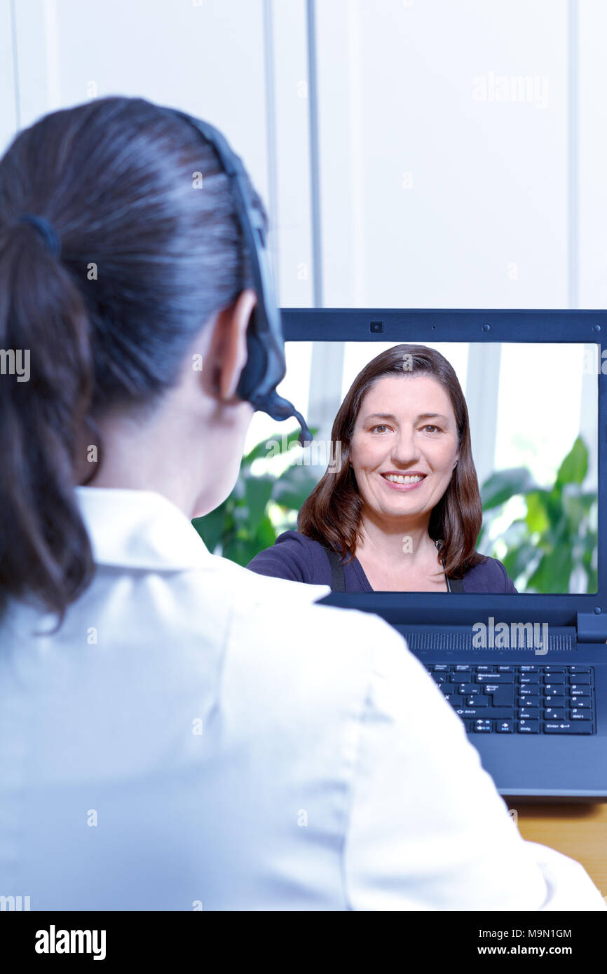 Arzt mit Headset vor Ihrem Laptop während einer online Beratung mit einem mittleren Alter weiblicher Patient, Telemedizin und e-health Concept Stockfoto