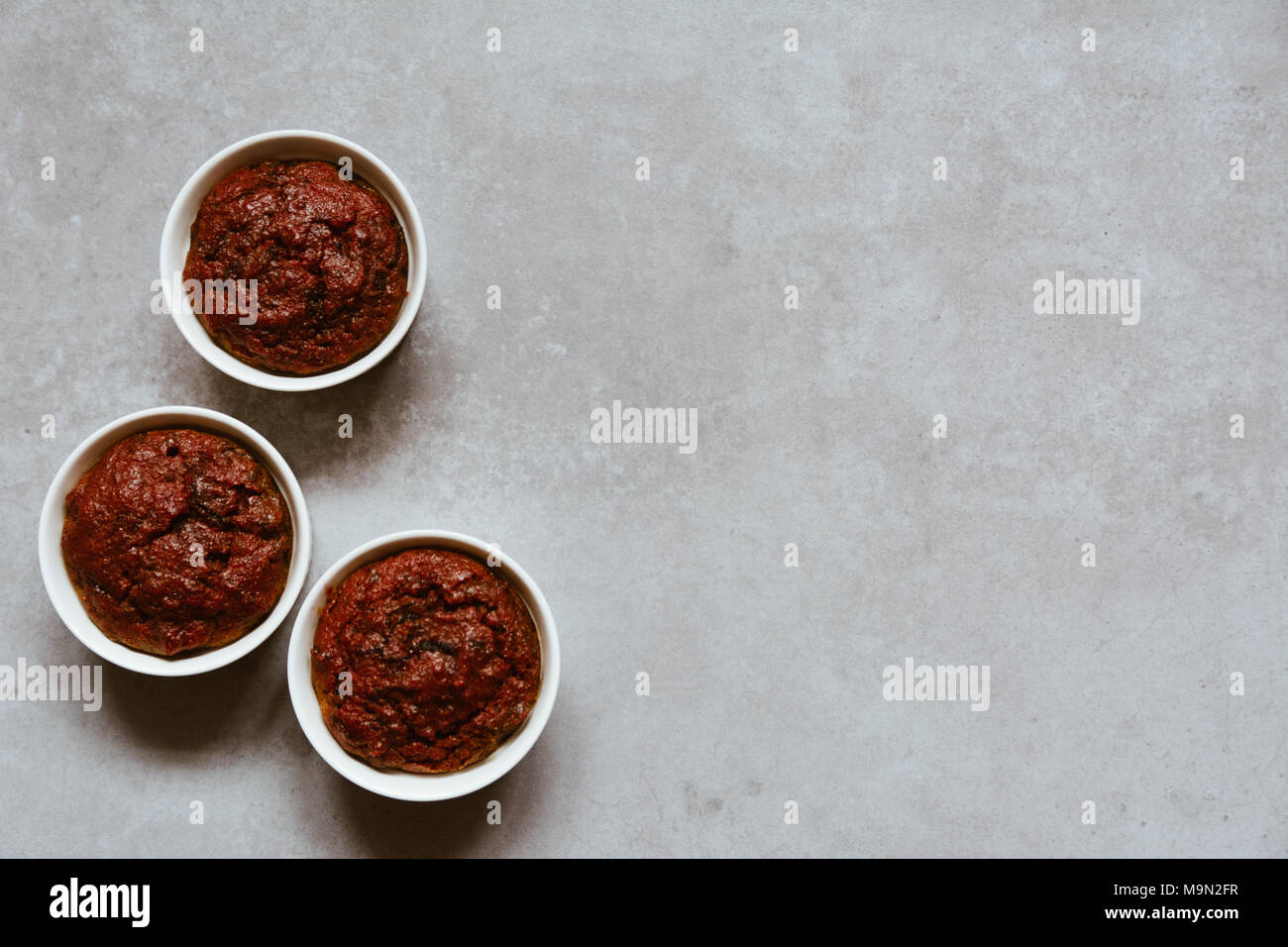 Gesund vegan Rote Bete Muffins in weißen Tassen auf rustikalen grau Brett. Festliche Komposition, Kopieren zur Verfügung. Flach. Film Stil. Stockfoto