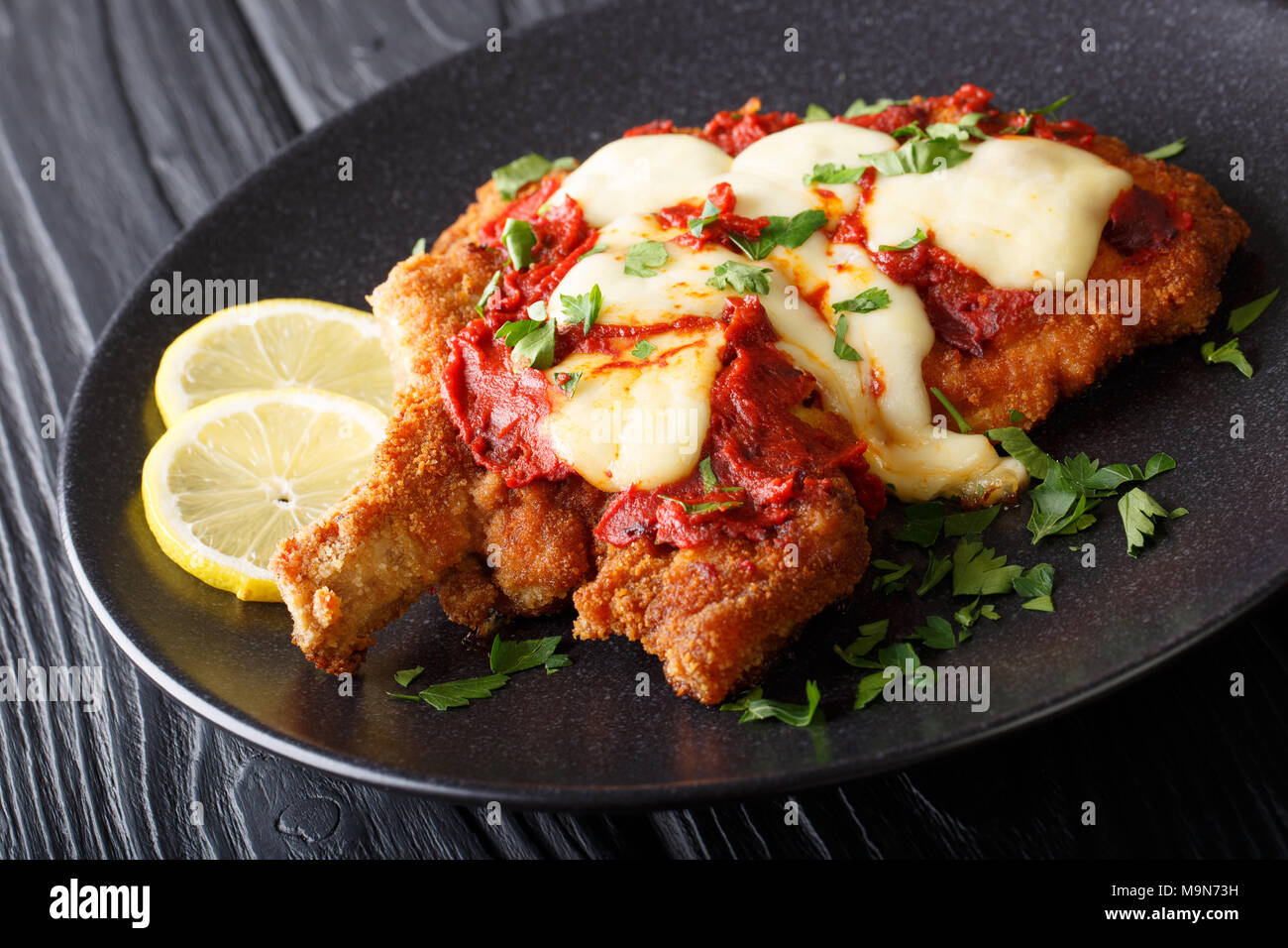 South American Food: Milanesa napolitana Rind Schnitzel paniert mit Mozzarella und Tomaten Sauce close-up auf einem Teller. Horizontale Stockfoto