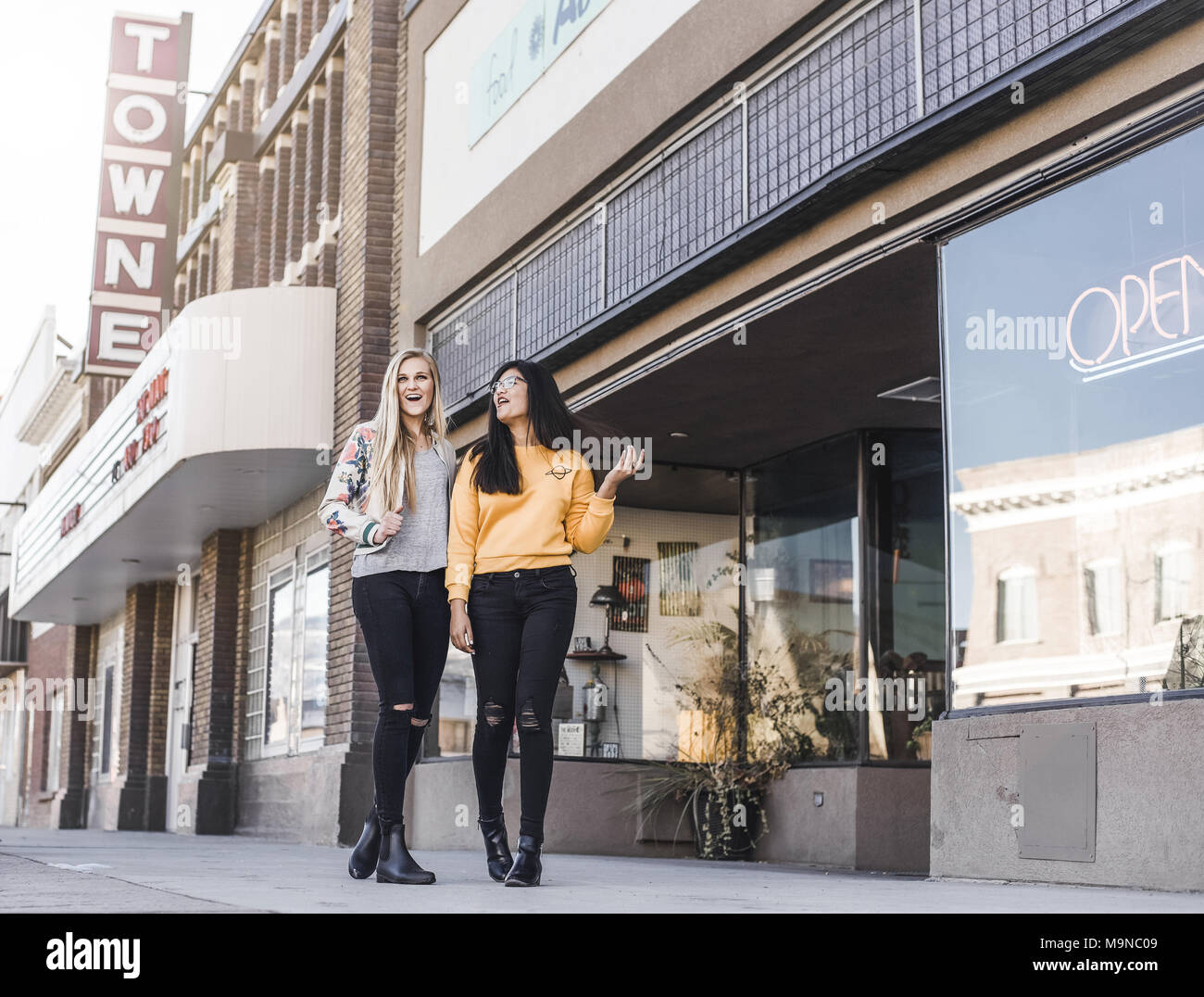 Zwei hübsche junge Mädchen lachen und gehen hinunter eine Straße in der Innenstadt in Utah Stockfoto