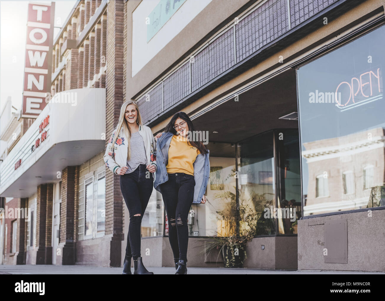 Zwei hübsche junge Mädchen lachen und gehen hinunter eine Straße in der Innenstadt Stockfoto