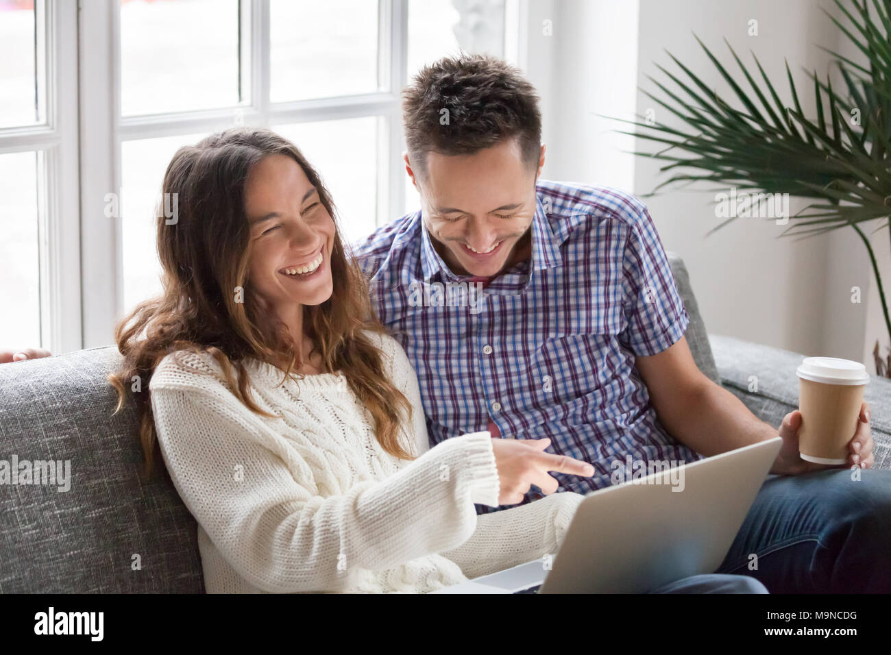 Junge glückliches Paar beobachten lustiges Video online, fröhliche Familie Spaß mit Laptop auf dem Sofa zu Hause, Freund und Freundin Freunde lachen Stockfoto