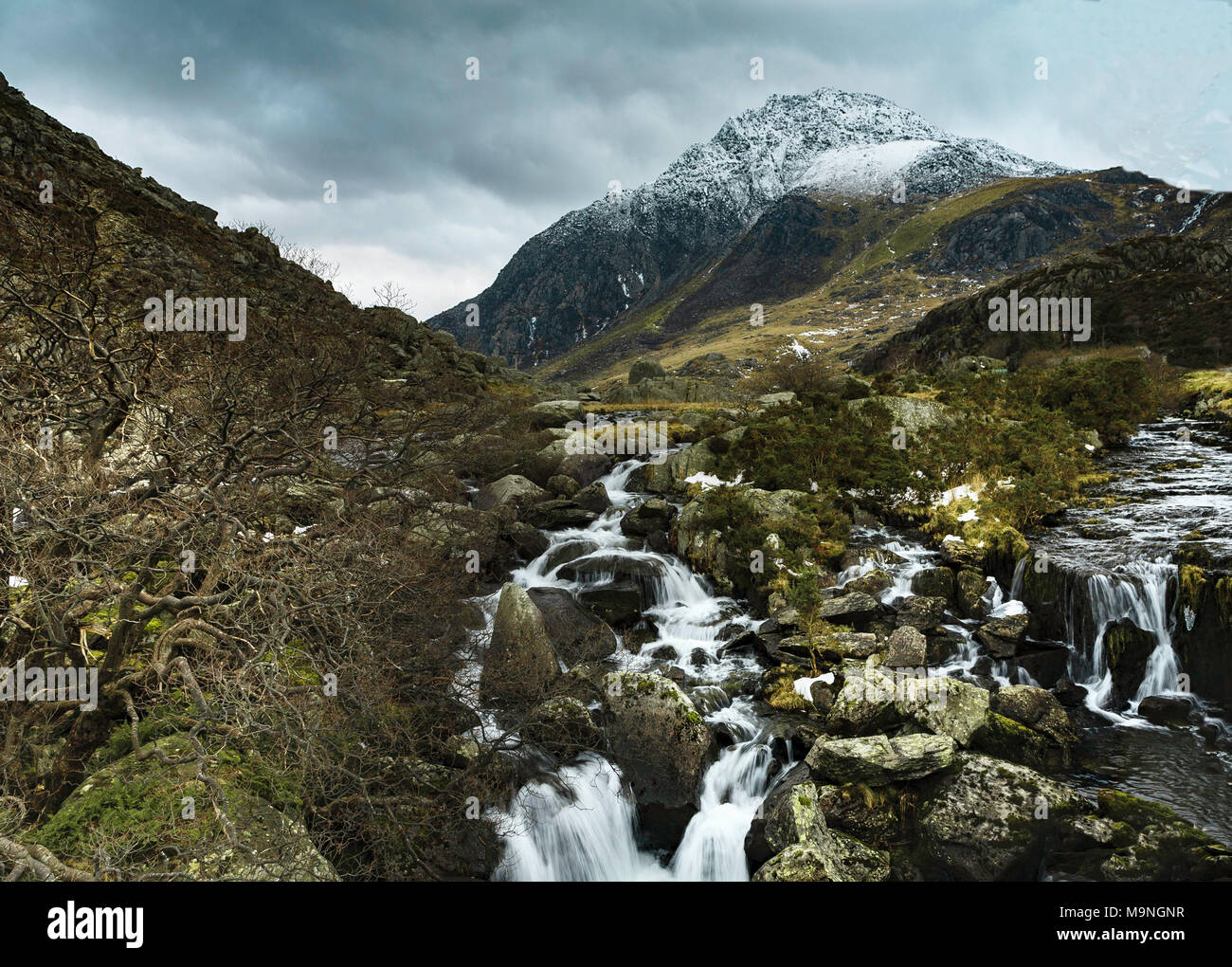 Einen schneebedeckten Berg mit Tryfan Afon Ogwen cascading seinen Weg den Berg hinunter in die Nant Ffrancon Tal. Stockfoto