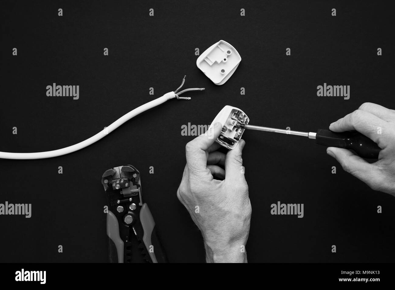 Elektrische Stecker eröffnet und ist offener Schraube einschrauben. Schwarzweiß gedreht Stockfoto