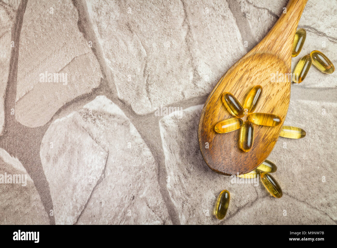 Lebertran Kapseln omega-3 auf Holzlöffel, rustikalem Stein Kulisse, flache Kopie Raum legen Stockfoto