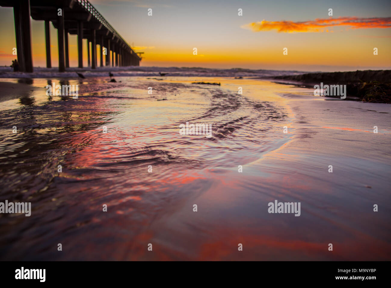 Sonnenuntergang reflektiert den Ozean Wasser neben einem Pier in Kalifornien. Stockfoto