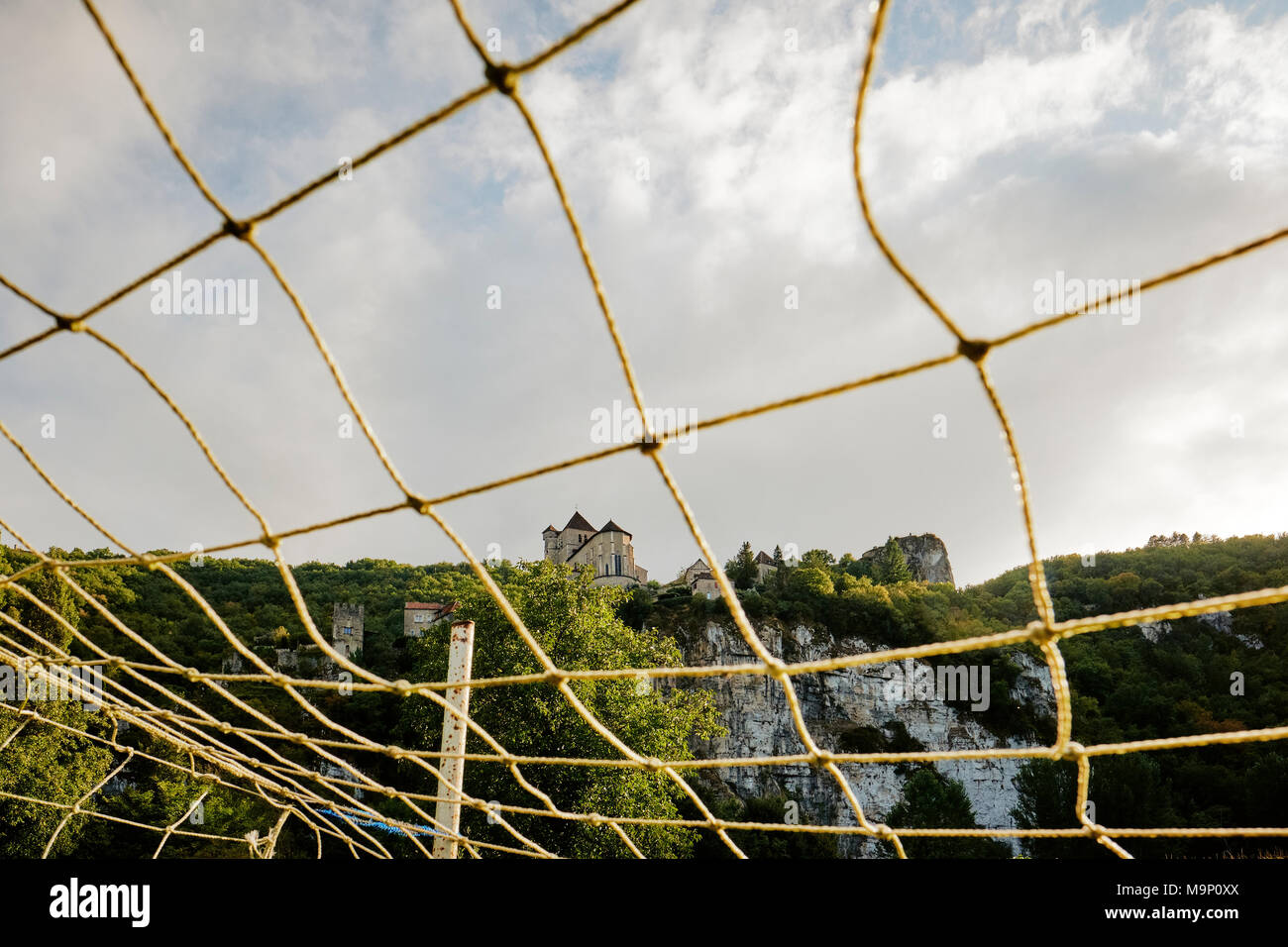 Ein fußballtor net Frames die mittelalterliche Stadt und Kirche von Saint-Cirq Lapopie, thront hoch auf einem Felsen im Tal des Lot. Stockfoto