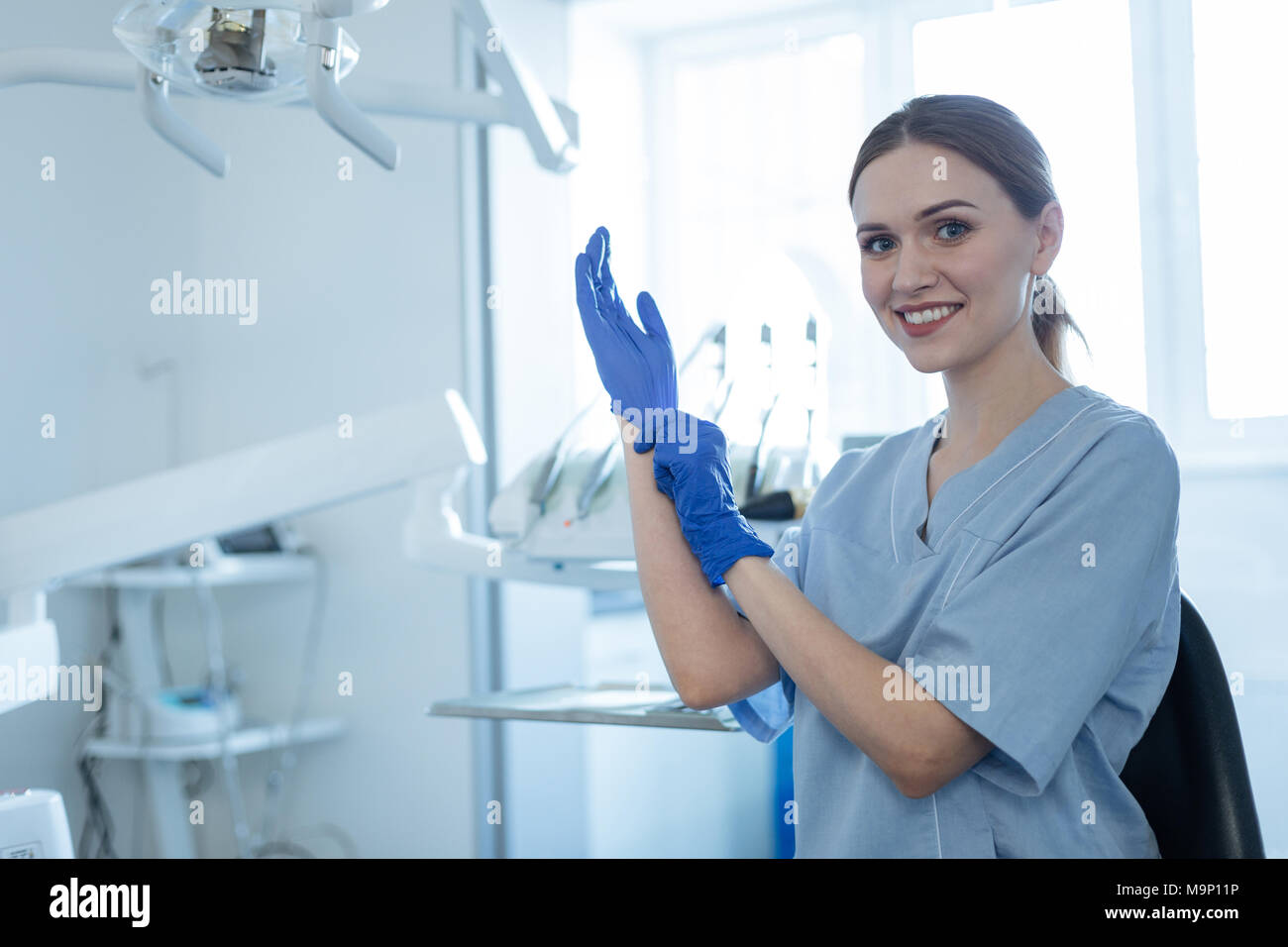 Upbeat weiblichen Zahnarzt setzen auf Gummihandschuhe Stockfoto