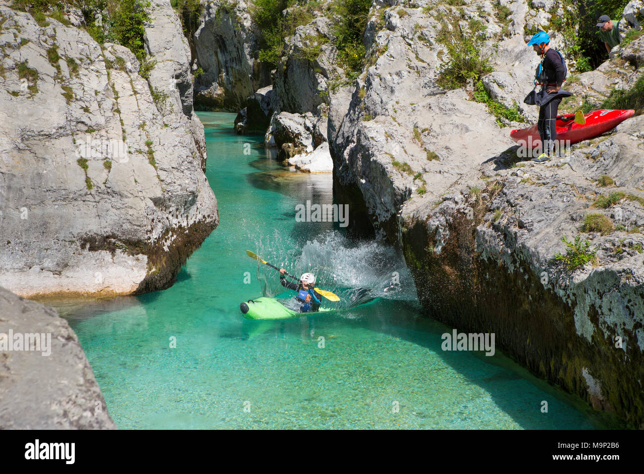 Ein Mann in einem Kajak ist ins Wasser springen, während ein anderer Mann beobachtet wird. Die smaragdgrüne Soca in der Nähe von Bovec in Slowenien, in der Triglav Gebirge mit Ursprung, ist berühmt für alle Arten von Wassersport. Stockfoto