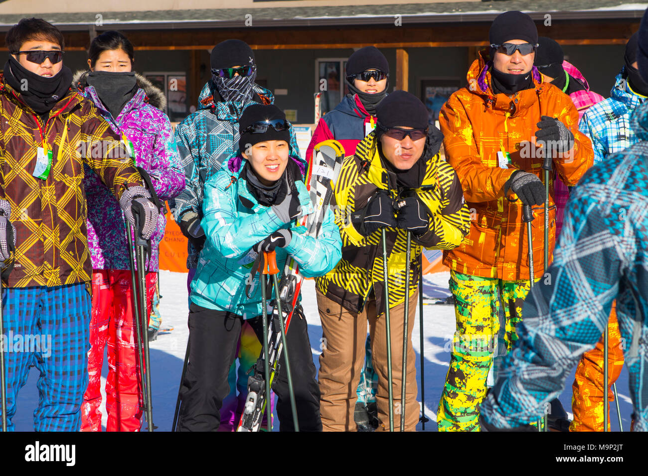 Eine Gruppe von jungen Koreaner an der Alpensia Resort in Südkorea. Traditionell Skifahrer Kleid in hellen Skianzüge. Die alpensia Resort ist ein Skigebiet und eine touristische Attraktion. Es ist auf dem Gebiet der Gemeinde von daegwallyeong-myeon befindet sich in der Grafschaft von Pyeongchang, die Olympischen Winterspiele hosting im Februar 2018. Das Skigebiet ist ca. 2,5 Stunden von Seoul oder Incheon Airport mit dem Auto, überwiegend alle Autobahn. Alpensia hat sechs Pisten für Ski und Snowboard, mit bis zu 1,4 km (0.87 mi) lang, für Anfänger und Fortgeschrittene, und einen Bereich für reserviert Stockfoto